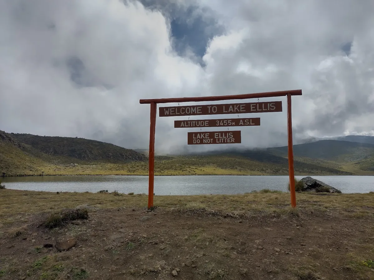 A mountain trail sign beside an alpine lake